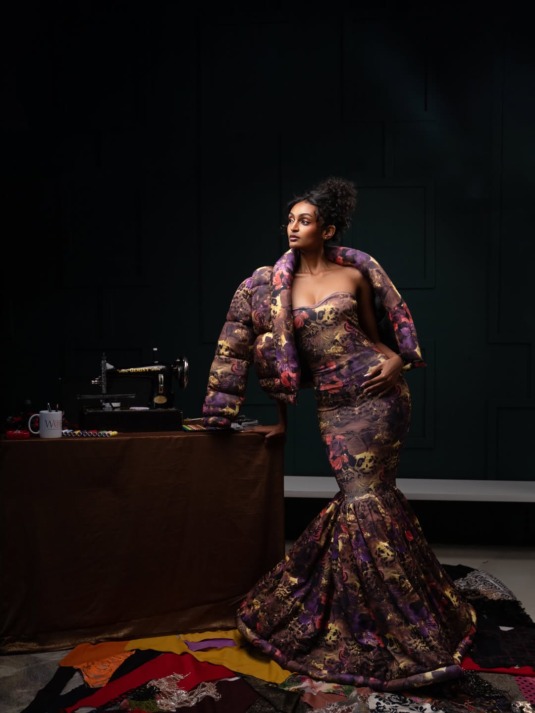 Model wearing the Sculptural gown beside an atelier sewing machine
